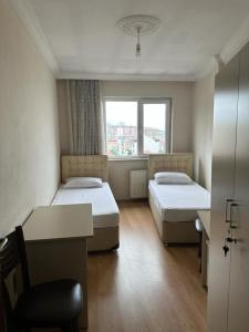 Zimmer mit 2 Betten, einem Schreibtisch und einem Fenster in der Unterkunft Kanarya Apart in Trabzon