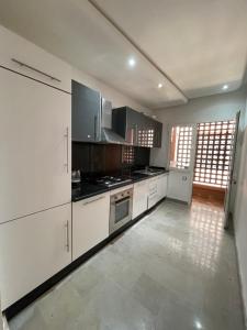 uma cozinha com armários brancos e electrodomésticos pretos em kechluxe em Marrakech