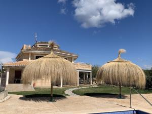 dwa kryte strzechą parasole przed domem w obiekcie Villa President Cosmos w Playa de Muro