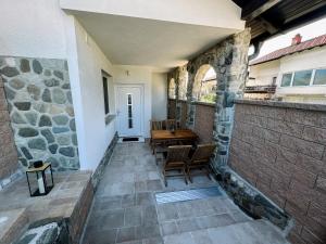 un patio con mesa, sillas y pared de piedra. en Apartment Neli, en Rečica ob Savinji