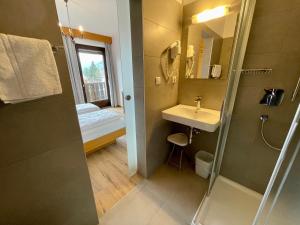 a bathroom with a shower and a sink and a mirror at Garni Transit B&B - Your Stopover in Vipiteno