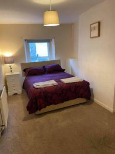 a bedroom with a bed with purple sheets and a window at Julia’s flat in Maryport