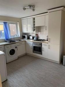 a kitchen with white cabinets and a washer and dryer at Julia’s flat in Maryport