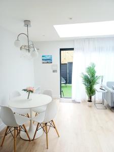 a white dining room with a white table and chairs at 'The Limes' - Air-Con Two Double Bedroom Holiday House with Private Garden in Kent