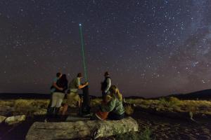 Un groupe de personnes debout autour d'un poteau dans les étoiles dans l'établissement Sanbona Wildlife Reserve, à Barrydale