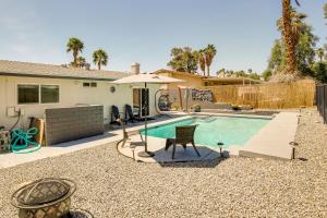 a pool with a chair and an umbrella next to a house at Palm Desert Vacation Rental with Private Pool and Spa! in Palm Desert