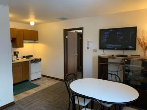 a small kitchen with a table and a tv on the wall at Destination Family Hotel in Whitehorse