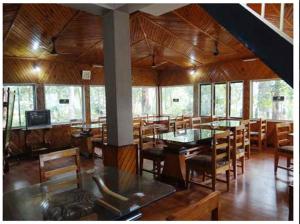 a dining room with tables and chairs in a building at Aranya Jungle Resorts in Lataguri