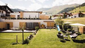 a yard with chairs and tables and a building at Hotel & Garni Das Köhle - inklusive der SUPER SOMMER CARD IM SOMMER 2024 in Serfaus