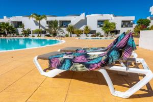 a lounge chair with a colorful blanket sitting next to a swimming pool at Casilla de Costa in Villaverde
