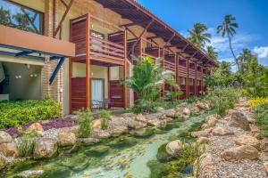 a house with a stream in front of it at Salinas Maragogi All Inclusive Resort in Maragogi