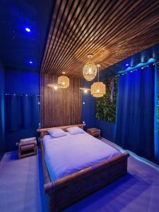 um quarto com uma cama grande num quarto azul em Suite Tropicale avec jacuzzi YaoSpa60 