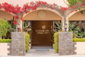 un ingresso a un hotel con fiori rossi di Casablanca Unique Hotel a Monte Gordo