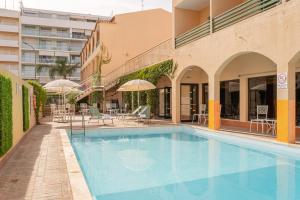 einen Pool in einem Gebäude mit Stühlen und Sonnenschirmen in der Unterkunft Casablanca Unique Hotel in Monte Gordo