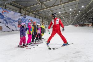 a group of children standing around a man on skis in the snow at Alpine Hotel by SnowWorld in Landgraaf