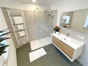 a white bathroom with a sink and a shower at Edle neue Ferienwohnungen in der Nähe der Bastei in Stadt Wehlen