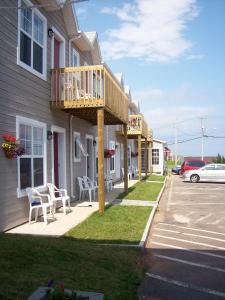 a building with a deck on the side of it at Hotel-Motel Le Panorama in Perce