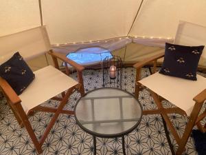 Zimmer mit 2 Stühlen und einem Tisch in einem Zelt in der Unterkunft Eakley Manor Farm Glamping in Newport Pagnell