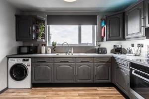 a kitchen with black cabinets and a washer and dryer at City home with parking and garden- pet friendly in Chester