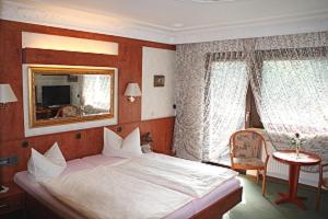 1 dormitorio con cama, espejo y silla en Hotel Kempenhof en Lügde