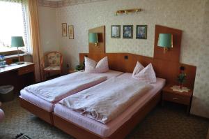 a bedroom with a large bed with white sheets at Hotel Kempenhof in Lügde