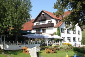 a large white building with tables and chairs in the yard at Hotel Kempenhof in Lügde