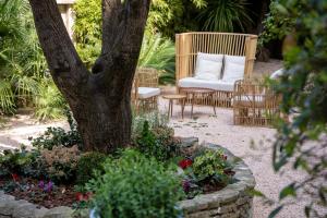 a garden with a chair and a tree and flowers at Le Clos Violette et Le 11 D'Aglaé - Hôtel de Charme Design de Luxe in LʼIsle-sur-la-Sorgue +127 photos