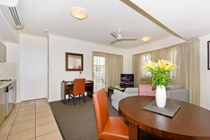 a kitchen and living room with a table and a couch at Metro Advance Apartments & Hotel in Darwin