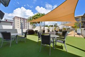 un patio con mesas y sillas en la azotea en Metro Advance Apartments & Hotel, en Darwin