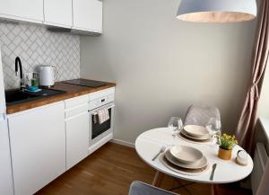 a white kitchen with a white table and chairs at Modern Smuuli apartment in Kuressaare