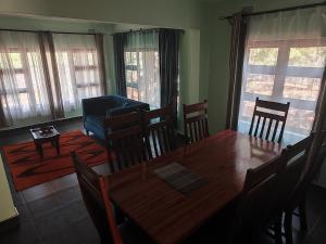 jadalnia z drewnianym stołem i krzesłami w obiekcie Kalahari Sand Ridge Inn w mieście Livingstone