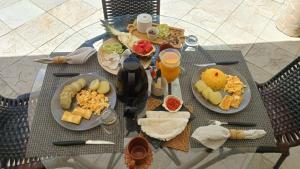 a table topped with plates of food and orange juice at Jardim Azul in Pitimbu