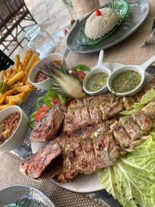 a plate of food with meat and vegetables and dips at Jardim Azul in Pitimbu