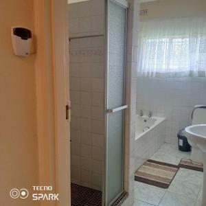 y baño con ducha, bañera y lavamanos. en Guesthouse with green garden and pool - 2102 en Harare