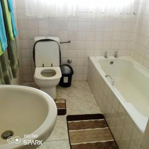 a bathroom with a tub and a toilet and a bath tub at Guesthouse with green garden and pool - 2102 in Harare