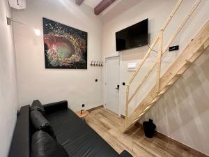 a living room with a couch and a tv and stairs at PACOROOMS in Madrid