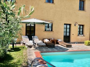 un patio con mesa y sombrilla junto a la piscina en Il Nido country house, en Montaione