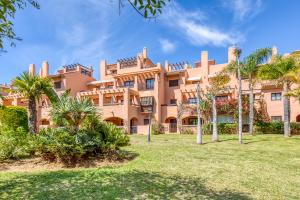 a large building with palm trees in front of it at Deluxe relax apartment with pool in Estepona