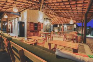a restaurant with wooden tables and wooden chairs and tables at Pousada Vilagoa in Coqueiro Sêco