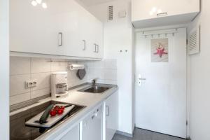 a kitchen with white cabinets and a sink at Burgtiefe Südstrand "Seestern" in Fehmarn