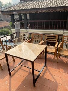 uma mesa de madeira e cadeiras num pátio em Aurora Backpackers Hostel em Luang Prabang