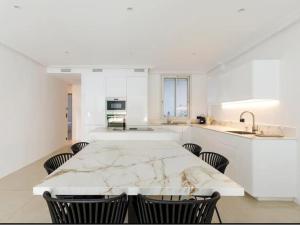 een witte keuken met een marmeren tafel en stoelen bij Appartement Avec Terrasse Centre-ville Croisette in Cannes