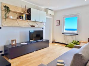 ein Wohnzimmer mit einem Sofa und einem TV in der Unterkunft CasaViva - Lovely SeaView Trilo in Genova Nervi in Genua