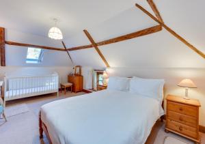 a bedroom with a large white bed and a crib at Leath Barn Cottage in Somerton