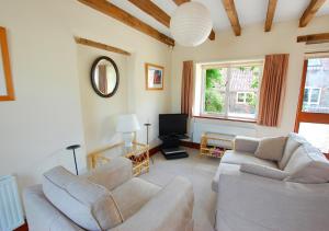 a living room with two couches and a tv at Church Barn Cottage in Saxlingham