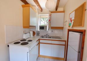 uma cozinha com um fogão branco forno ao lado de um lavatório em Church Barn Cottage em Saxlingham