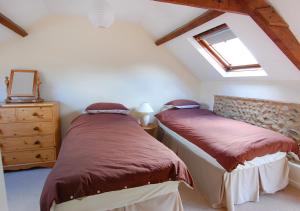 2 camas individuais num quarto no sótão com uma janela. em Church Barn Cottage em Saxlingham