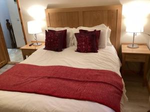 duże łóżko z czerwono-białą pościelą i poduszkami w obiekcie Abby's Cottage Roundstoneselfcatering w mieście Roundstone