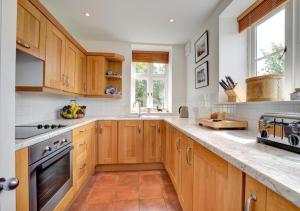 a kitchen with wooden cabinets and a stove top oven at The Old Chapel in Hindolveston