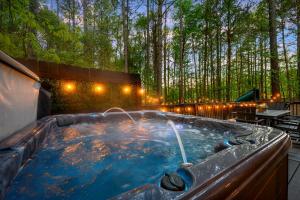 a hot tub in the middle of a forest at Hickory Bear - Cabin surrounded by pines, Sleeps 10, Hot Tub, Fire Pit, Arcade, Foosball Table & Deck Slide in Broken Bow